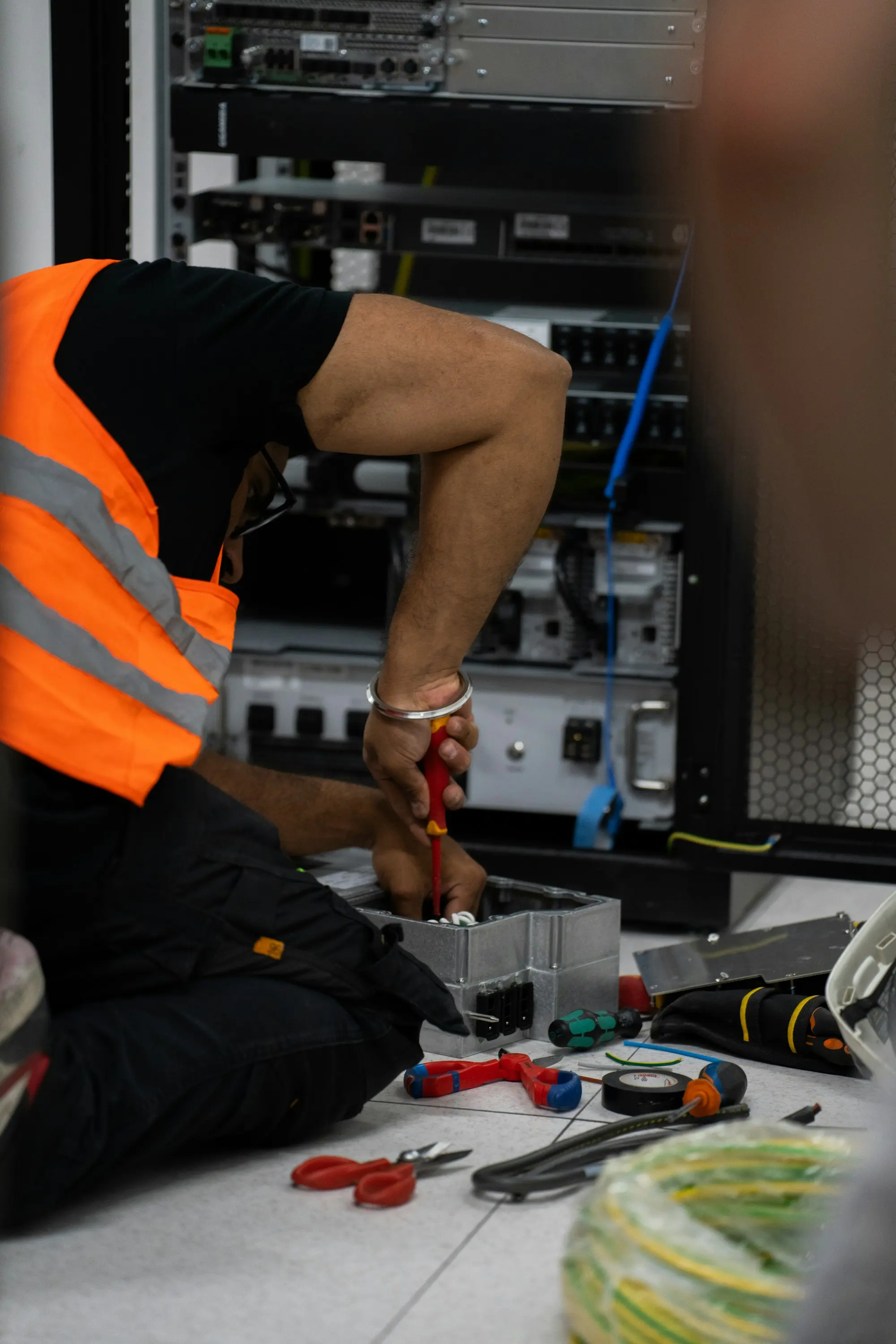A technician's hands working on equipment inside an open network cabinet.